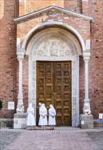 Nuns contemplate the Porta Santa of the Abbey Church of San Silvestro