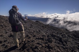 Hiker on the Piton de la Fournaise volcano with views of the Piton des Neiges volcano