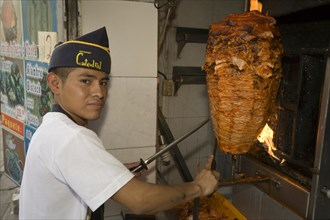 Young man preparing tacos al pastor