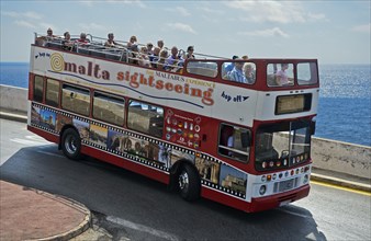 Tourists in an open-top double-decker bus on an excursion at the coast