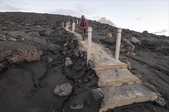 Woman climbing stairs to the crater of Mount Yasur volcano