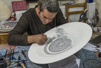 Artisan painting a large ceramic bowl
