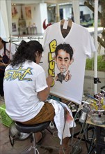 Woman airbrushing a portrait on a T-shirt