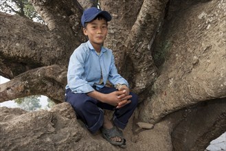 Nepalese student wearing a school uniform sitting on a tree