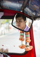 Tuktuk taxi driver reflected in the rear mirror during the ride
