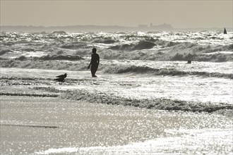 Woman in front of the surf of the North Sea in backlight