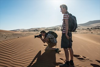 Two teenagers standing on a dune