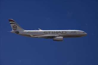 A6-EYK Etihad Airways Airbus A330-243 in flight against a blue sky