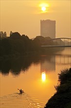 A canoeist on the Rhine-Herne Canal at sunset with Gasometer