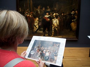 Visitor watching the painting The Night Watch by Rembrandt at the Rijksmuseum