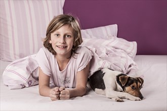 Girl lying in bed with a Danish Swedish Farmdog