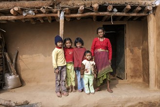 Old Nepalese woman and four children in front of a typical Nepalese rural house