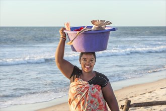 Malagasy woman carrying fish in a tub on her head