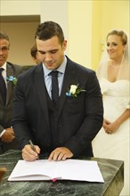 Groom signing the church register after the ceremony