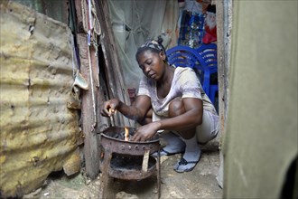 Woman cooking in the improvised kitchen of an ramshackle hut