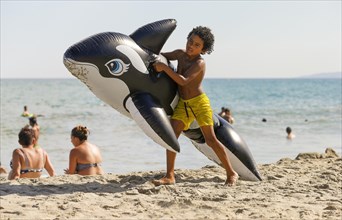 Boy with an inflatable water toy on the beach