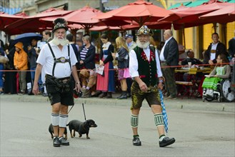 Two Munich men in traditional costume with a Dachshund