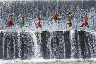 Boys jumping in a waterfall and having fun