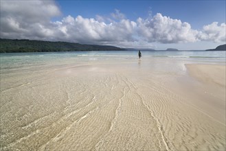 Woman walking across a sandbank to the beach