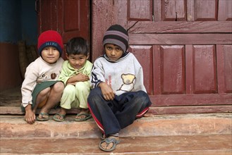 Nepalese children sitting in front of a doorway