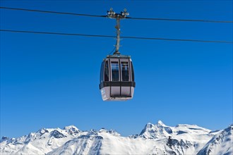 Gondola of the Moosfluh cable car in front of the snowy mountain range of the Valais Alps