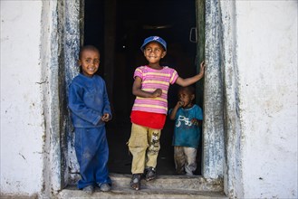 Young children standing in a door frame