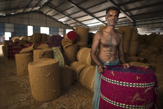 Worker with rolled coconut fibre mats or coir mats