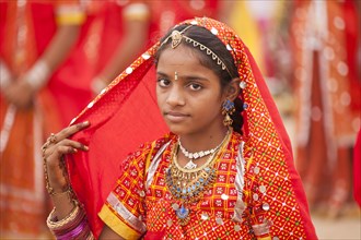 Portrait of a young woman in typical colourful traditional Rajasthani costume at the camel market and livestock market