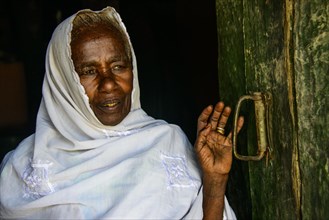 Friendly old woman standing in a door frame near Keren