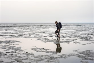 Young woman walking in the mudflats of the Wadden Sea at low tide