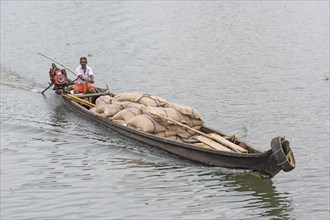Man steering a boat laden with sacks