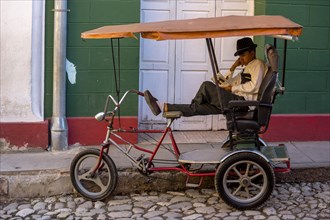 Rickshaw driver waiting for customers and reading a book