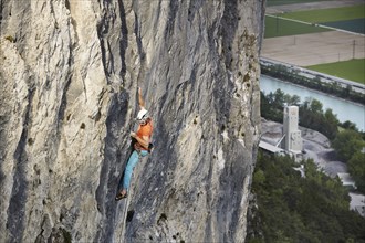 Freeclimber with helmet climbing on a rock face