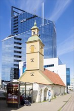 Wooden church in front of modern building of SEB bank in the financial and business district