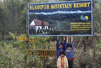 Children in front of a billboard for the Bandipur Mountain Resort