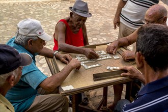 Cuban men playing dominoes at a table outside