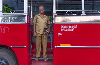 Bus driver in front of a red bus