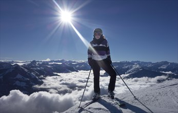 Young woman with ski equipment against Alps mountains