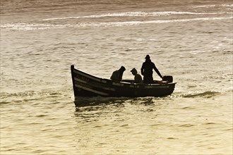 Silhouettes of three fishermen in a small boat