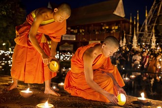 Young monks lighting candles during the Macha Pucha celebration at Wat Pan Tao