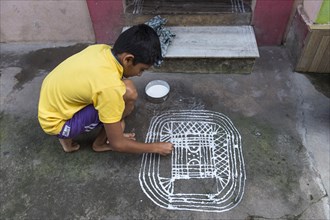Boy painting a traditional Rangoli