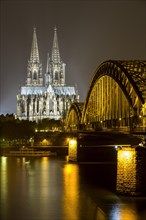 The illuminated Cologne Cathedral and Hohenzollern Bridge at night with Rhine