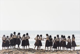 Girl school class in school uniforms at the beach