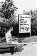 Man in swimming trunks on a bench on the shore of the Senftenberg dredging lake