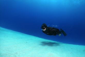 Freediver diving along sandy bottom