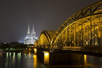 The illuminated Cologne Cathedral and Hohenzollern Bridge at night with Rhine