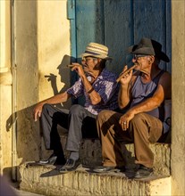 Two elderly Cubans sitting on a doorstep in the evening light