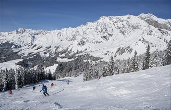 Skiers on ski slope in front of mountain scenery