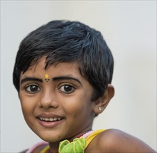 Girl with yellow bindi on the forehead and kohl-rimmed eyes