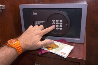 Person typing a PIN into a closed safe